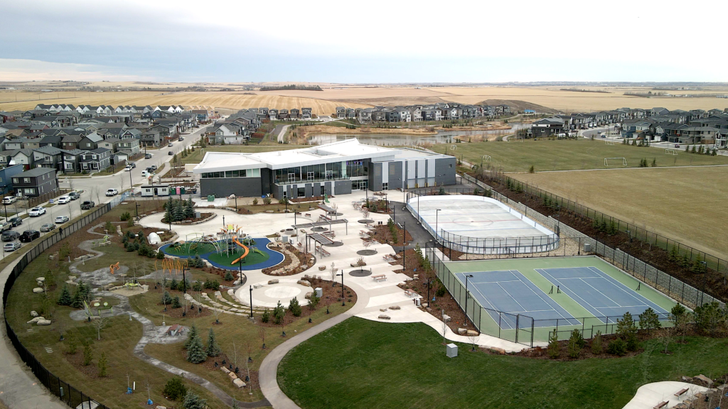 Modern Livingston HOA community center, The Hub, featuring indoor gym, basketball courts, and outdoor splash park for year-round family activities in NE Calgary.